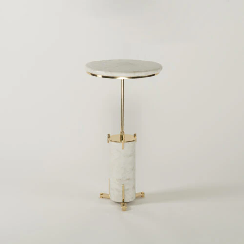 The HELIOS END TABLE features a round white marble top, slender gold metal stem, and cylindrical marble base with gold accents and three gold feet, shown against a plain white background.