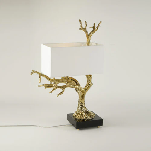 The ALBERO TABLE LAMP features a gold tree-branch-shaped base, a rectangular white lampshade, and sits on a black square platform with an electrical cord.