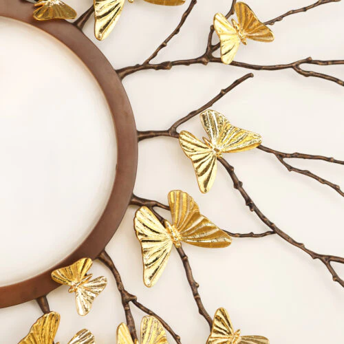 Close-up of the AVA FLUSH MOUNT, showcasing a brown circular frame with gold metallic butterflies on branch-like extensions for an elegant, nature-inspired look.