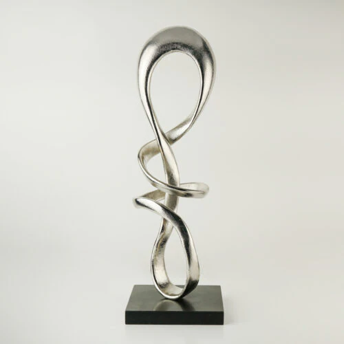 The ALTAIR SCULPTURE is a modern abstract piece featuring silver metal intertwined loops, standing upright on a black rectangular base against a plain white background.