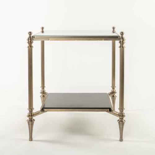 The MEDFORD END TABLE features a glass top, gold-toned metal frame, four slender fluted legs, and a black lower shelf in an elegant, minimalist design. Shown against a plain white background.